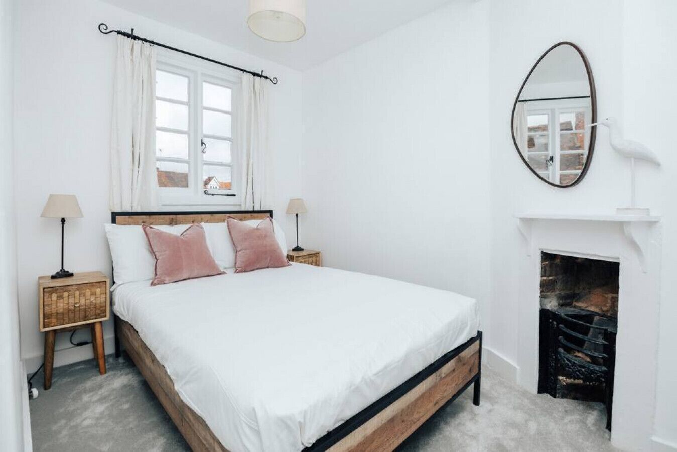 Un dormitorio con cama, chimenea y ventana con cortinas.