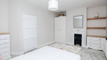 Un dormitorio con cama, armario, cómoda, espejo y chimenea.