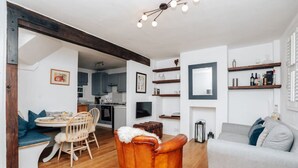 A modern living room with a grey sofa, a brown leather chair, and a dining area with a wooden table and chairs.