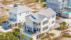 A multi-story beachfront property with a pool, multiple balconies, and a boat dock.