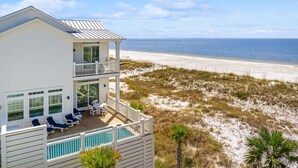 A beachfront property with a two-story building, a balcony with outdoor seating, and a view of the ocean.