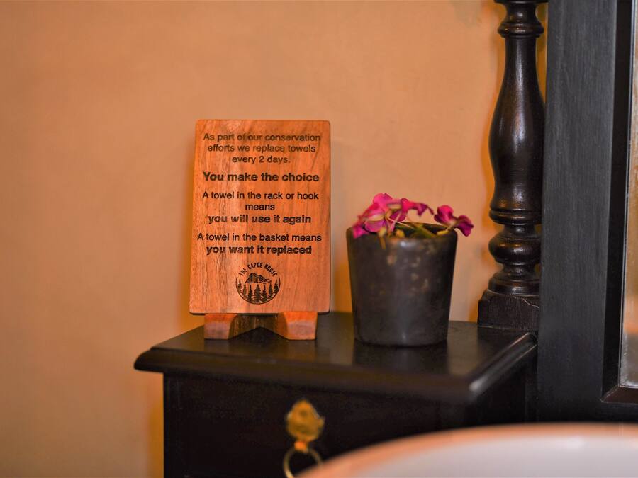 A wooden sign with conservation message, a small potted plant, and a dark wooden dresser.