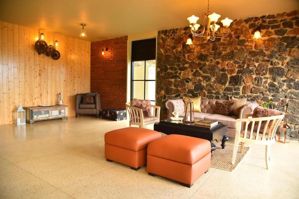 A cozy living room with a stone wall, wooden paneling, and a fireplace. There are two sofas, a coffee table, and a rug.