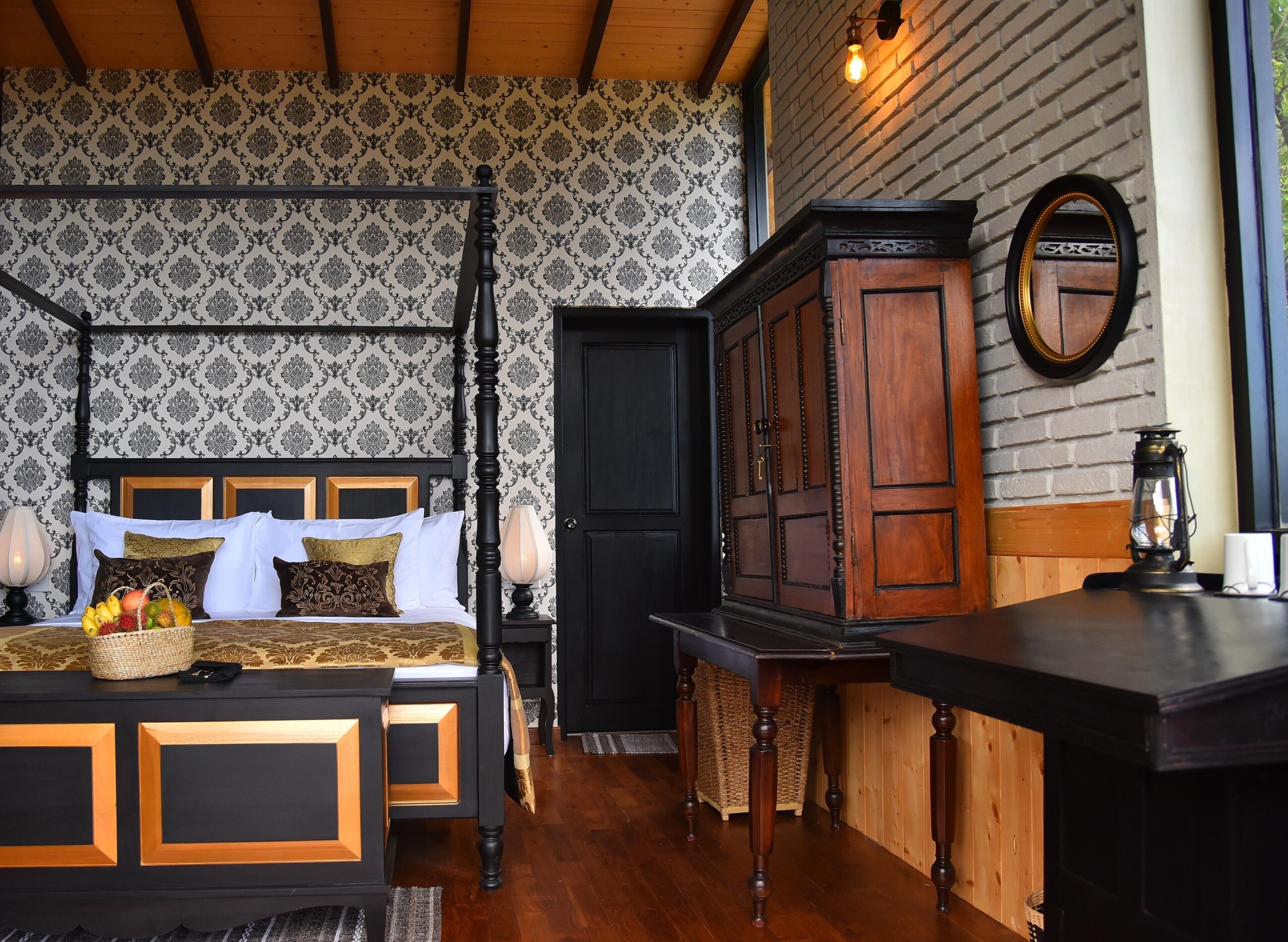 A four-poster bed with a headboard, a wooden cabinet, a small table, and a mirror on the wall.