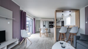 A modern living space with a dining area, kitchen, and seating area. - Beautiful Chalet for 4 people - Heated pool access (Bretignolles-sur-Mer)