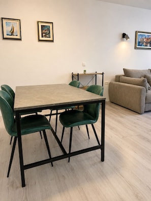 Un coin repas avec une table et des chaises, un canapé et deux tableaux encadrés au mur.
