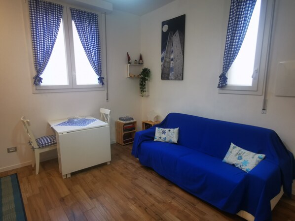 A room with a blue sofa, a white desk, and a window with blue curtains. - B&BO - DREAM IN BOLOGNA - APARTMENT - FREE PARKING (BOLOGNA)