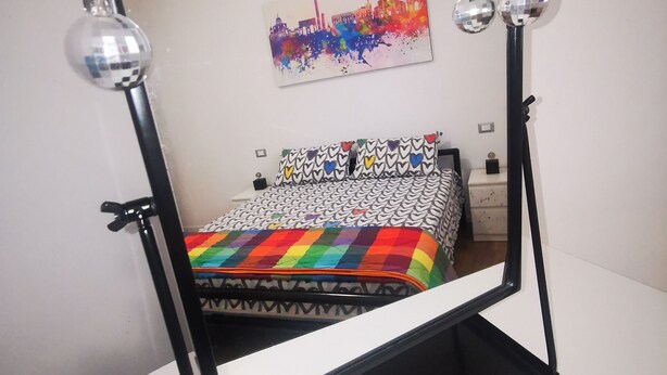 A bed with a colorful quilt, a black metal frame, and a mirror with decorative elements. - B&BO - IN BOLOGNA YOU DREAM - APARTMENT - FREE PARKING  (BOLOGNA)