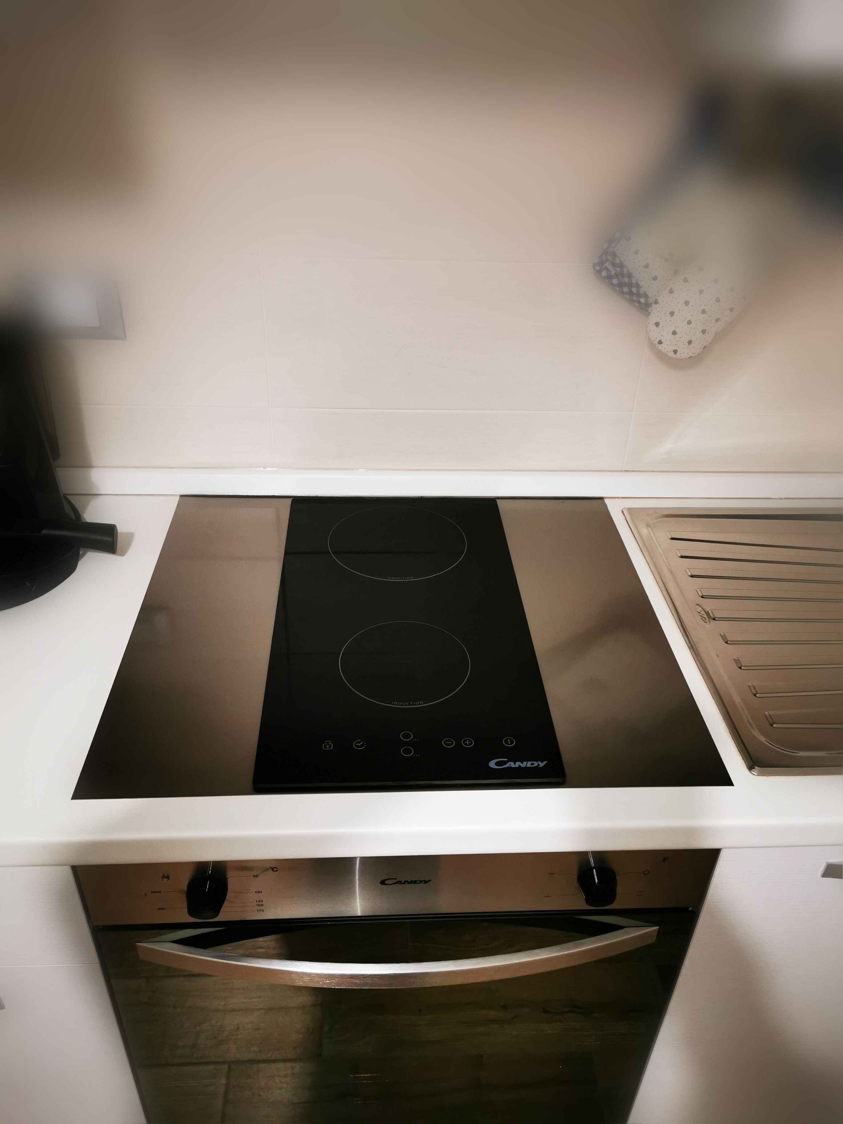 Eine Küche mit einem schwarzen Induktionskochfeld, einem Backofen und einer Mikrowelle.