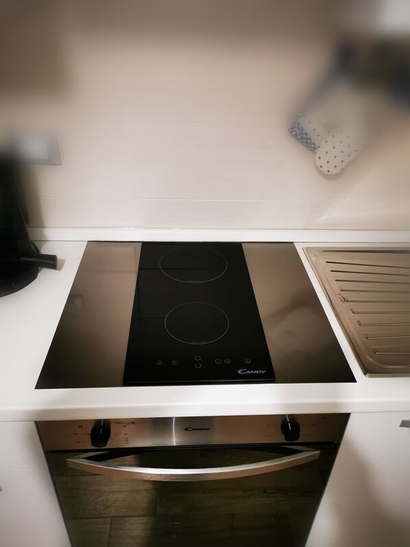 A kitchen with a black induction cooktop, a built-in oven, and a microwave.
