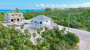 A beachfront property with a partially constructed building and a completed house with a balcony.