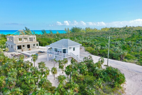 Une propriété située en bord de mer, comprenant un bâtiment en construction et une maison achevée dotée d’un balcon.