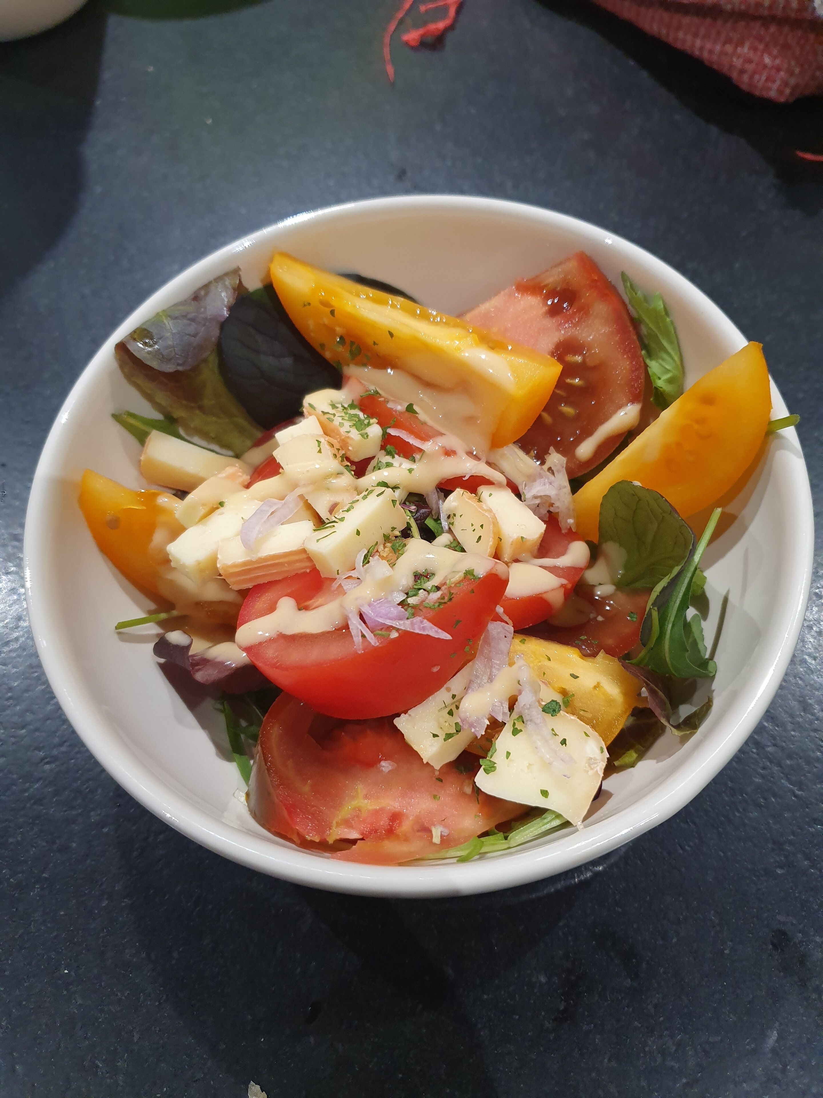 A bowl of salad with various vegetables and cheese.