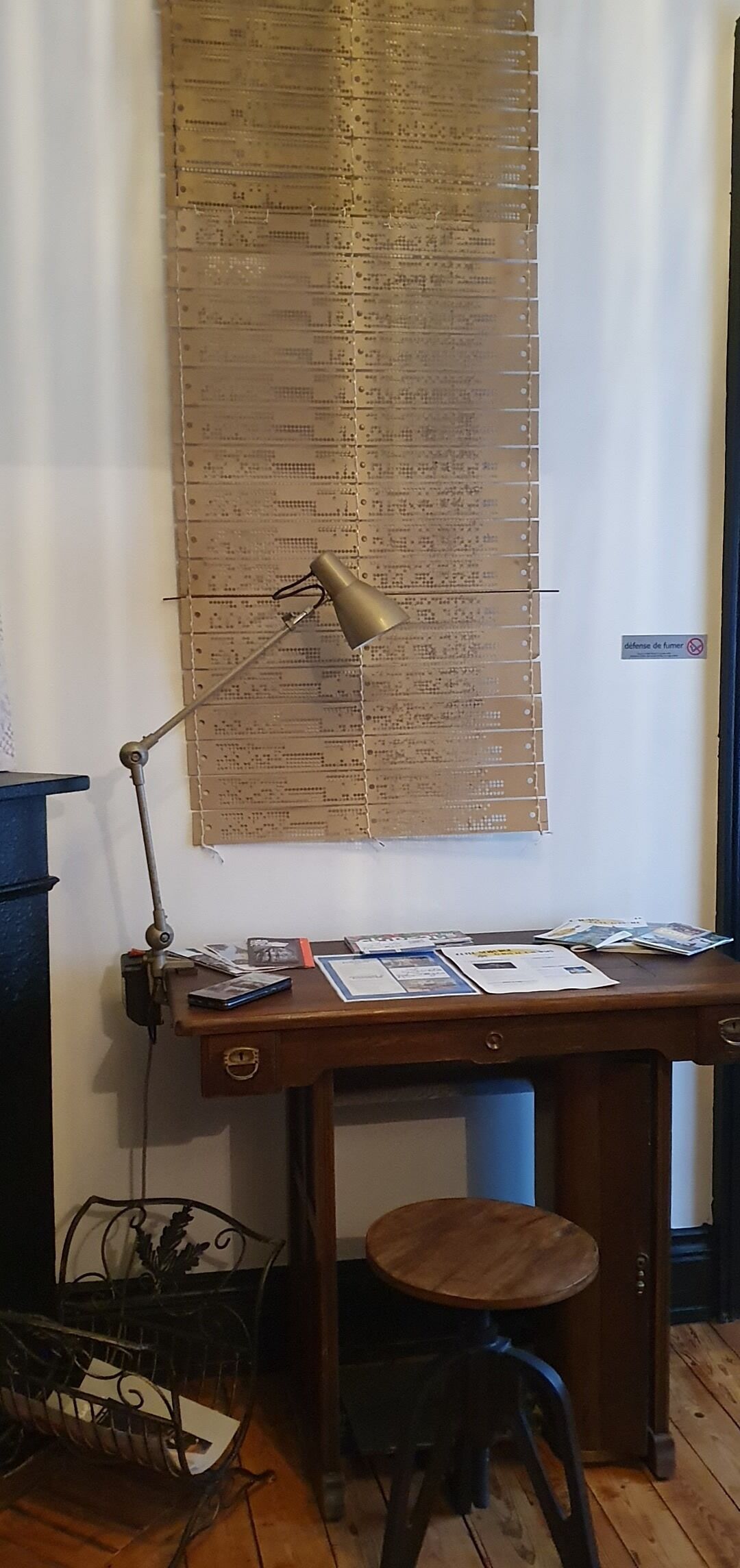 A desk with a lamp, papers, and a chair in a room with wooden flooring.