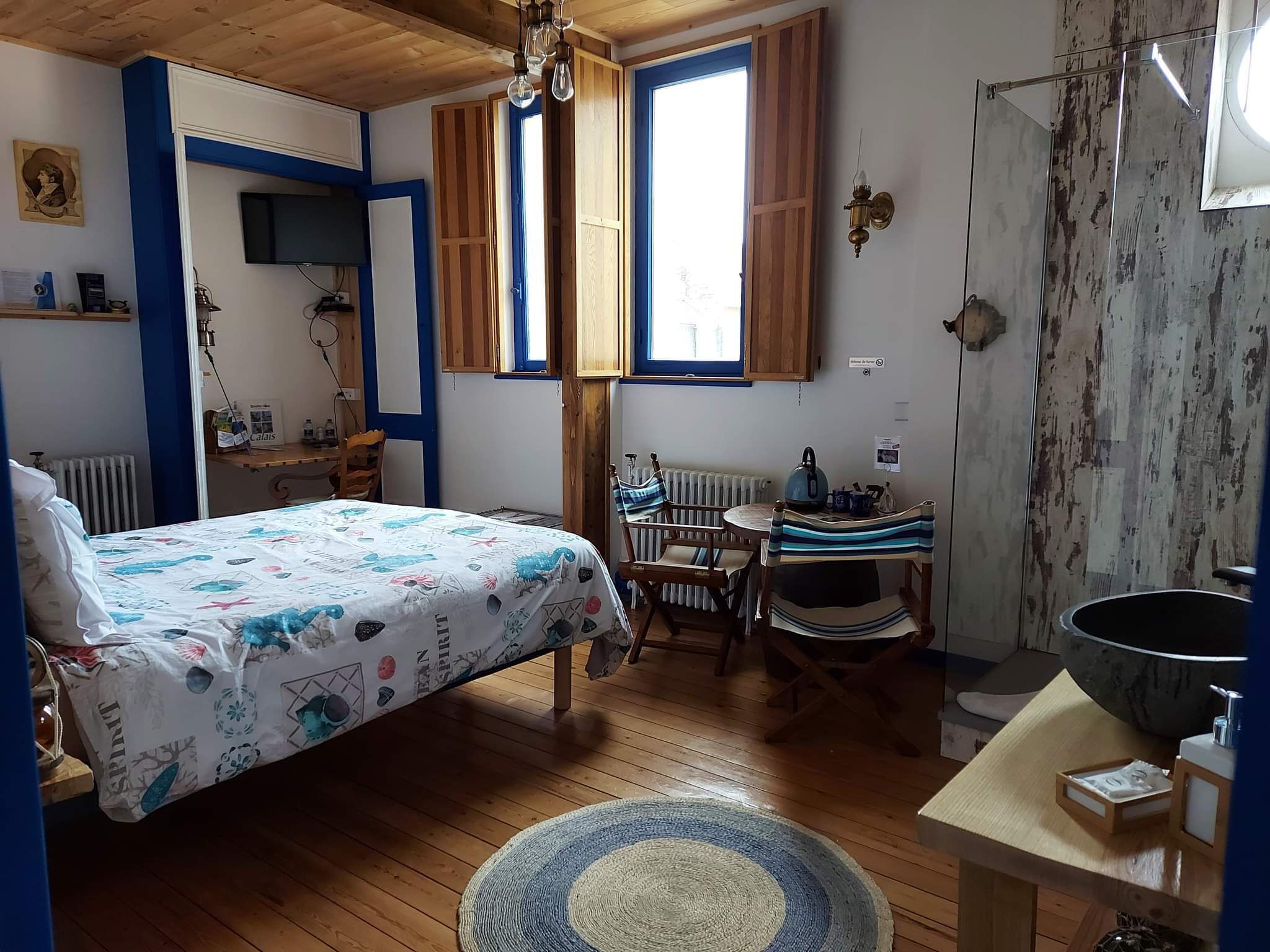A cozy bedroom with a bed, a desk, and a bathroom.