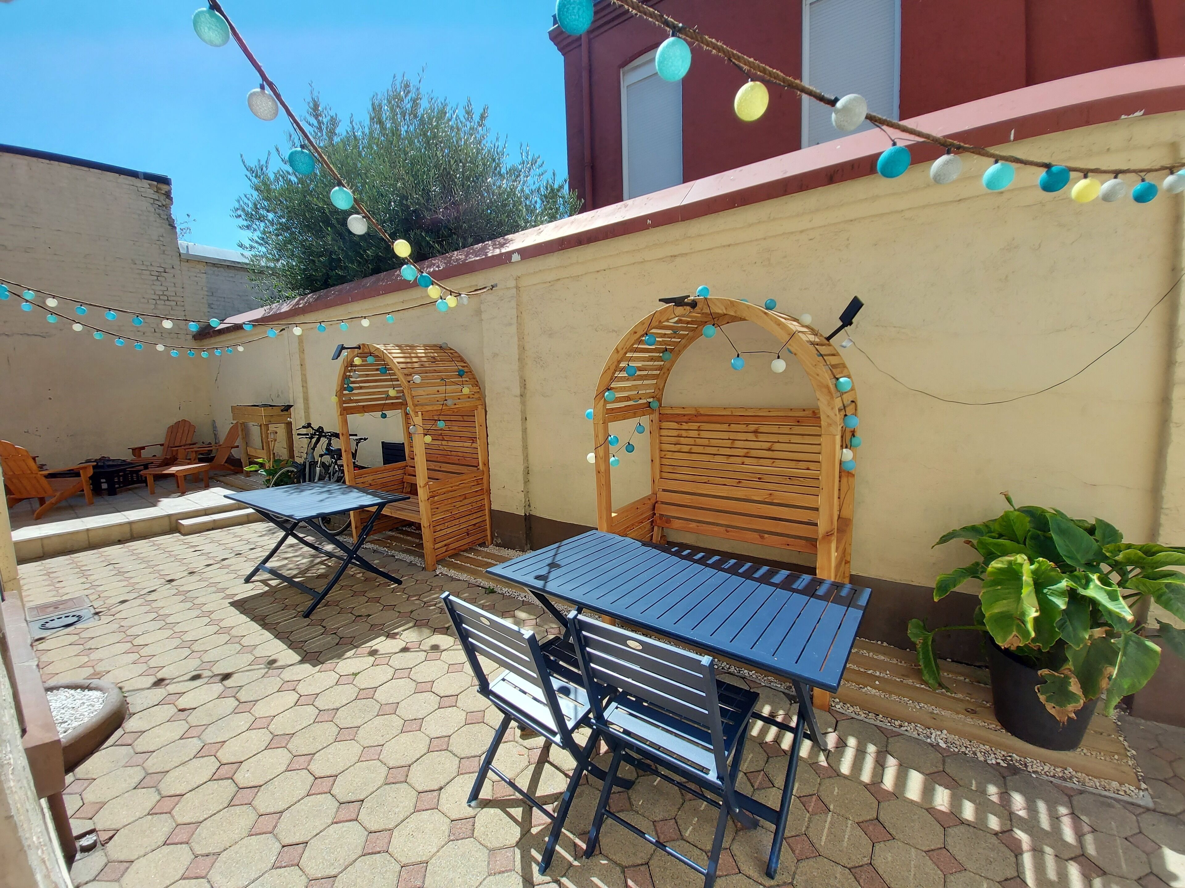 An outdoor patio with hexagonal tiles, wooden furniture, and string lights.