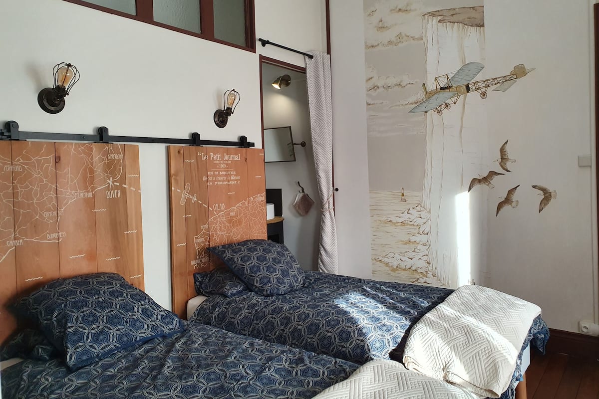 A bedroom with a bed, a wooden headboard with a map, and a wall mural of birds.