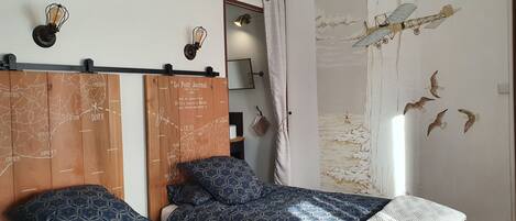 A bedroom with a bed, a wooden headboard with a map, and a wall mural of birds.