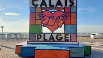 Un muelle con un cartel grande que muestra distancias a ciudades y un corazón con alas.