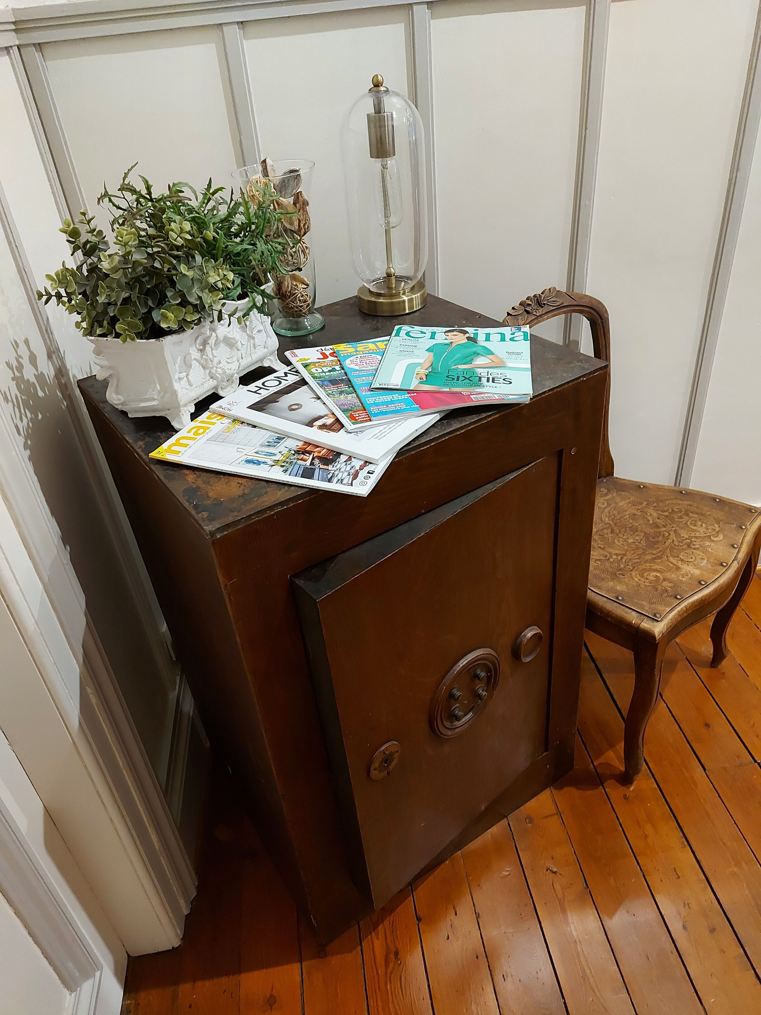 Un aparador de madera con una planta en maceta y revistas encima.