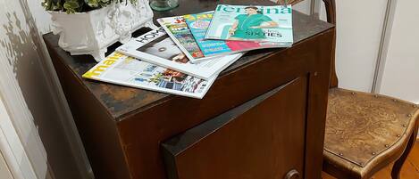 Un aparador de madera con una planta en maceta y revistas encima.