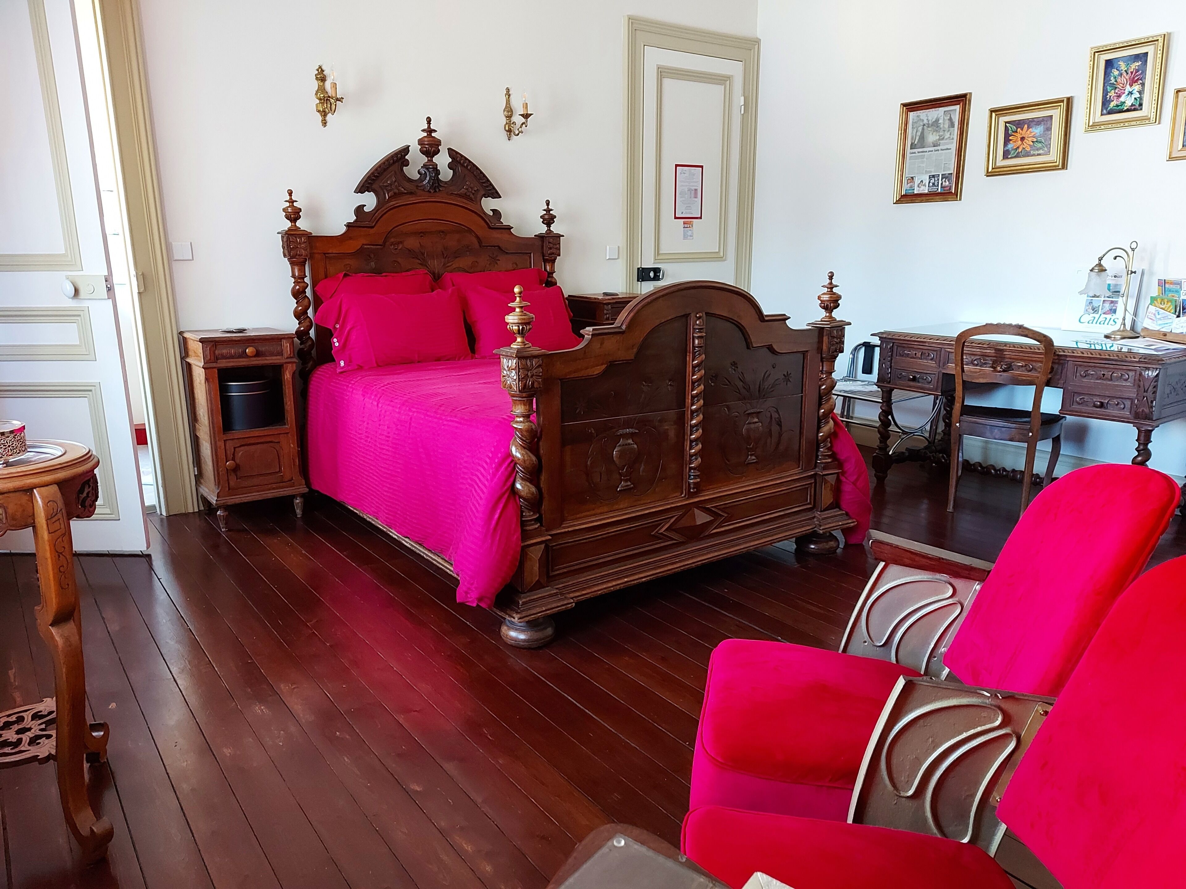 A traditional bedroom with a wooden four-poster bed, a desk, and a chair.
