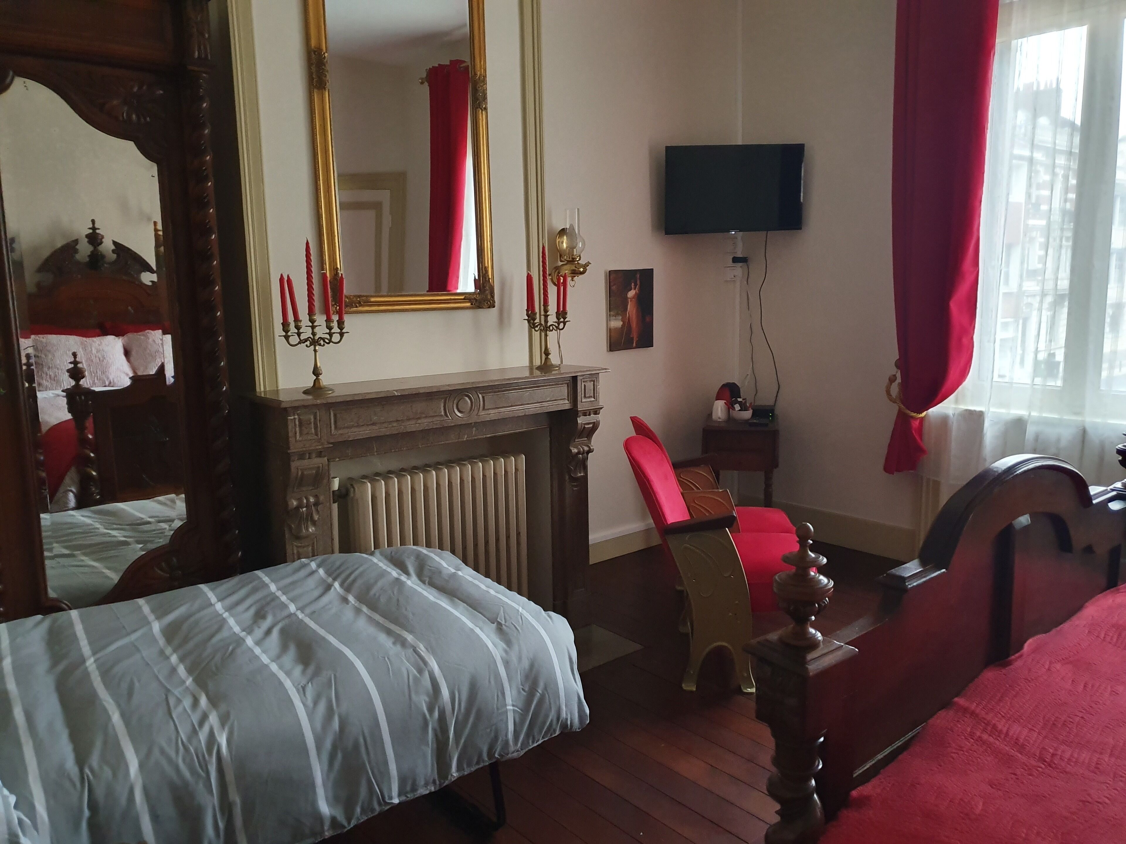 A bedroom with a bed, a chair, a TV, and a fireplace.