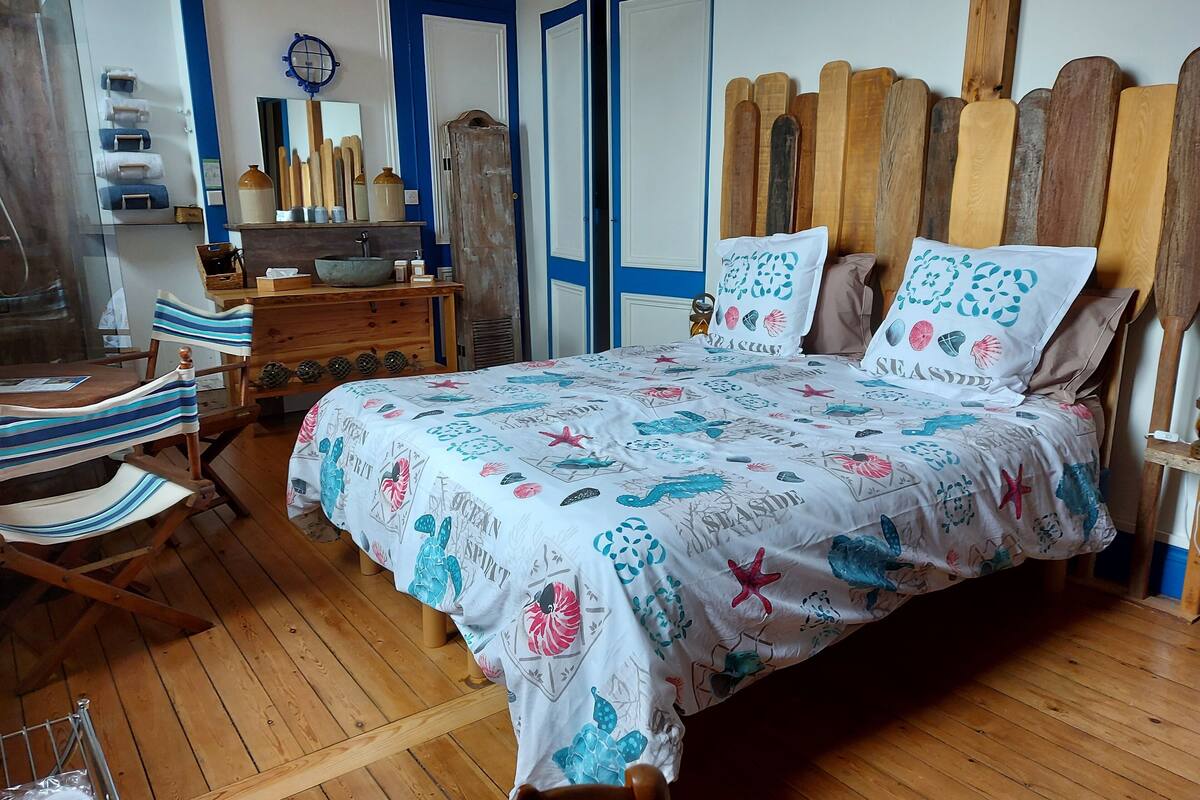 A bedroom with a wooden bed, striped chairs, a wooden dresser, and a blue and white color scheme.