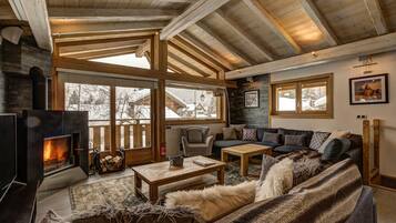Un salon chaleureux avec une cheminée, des meubles en bois et de grandes fenêtres.