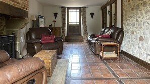Una sala de estar acogedora con sofás de cuero, chimenea, paredes de piedra y piso de baldosas.