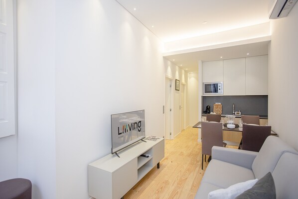 Un salon moderne avec un téléviseur à écran plat, un meuble de rangement blanc et un canapé gris.