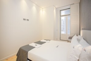 Une chambre d’hôtel moderne, équipée d’un lit, d’une petite table et d’une porte donnant sur un balcon.
