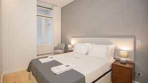 A neatly arranged bedroom with a bed, bedside tables, and a chair.
