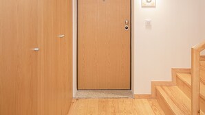 A wooden door with a light switch and a wall-mounted light fixture with a letter 'B'.