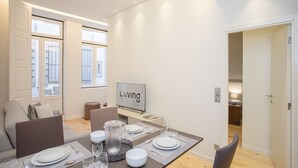 A modern dining area with a set table, a television, and a view of the city through large windows.
