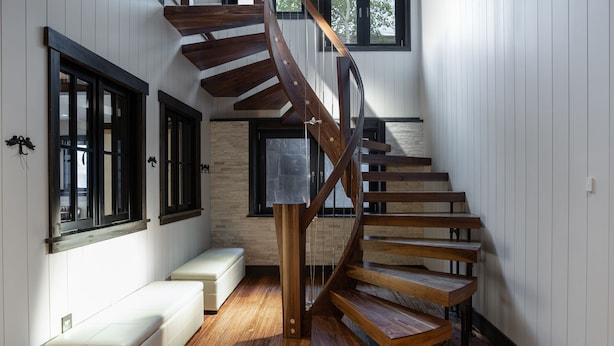 Un escalier en colimaçon avec des marches en bois et une colonne centrale, menant à l’étage supérieur.