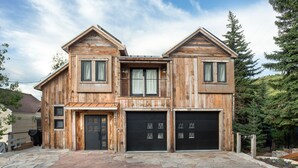 Une maison en bois à deux étages, avec une allée pavée de pierres et un garage.