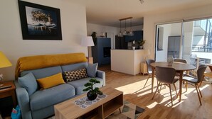 Een woonkamer met een bank, salontafel en een eethoek met stoelen en een tafel.