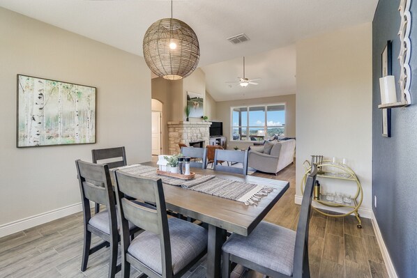 A dining area with a wooden table, grey upholstered chairs, and a hanging light fixture.