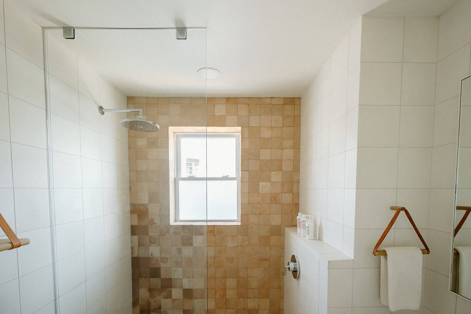 A modern bathroom with a shower, a window, and a towel rack.