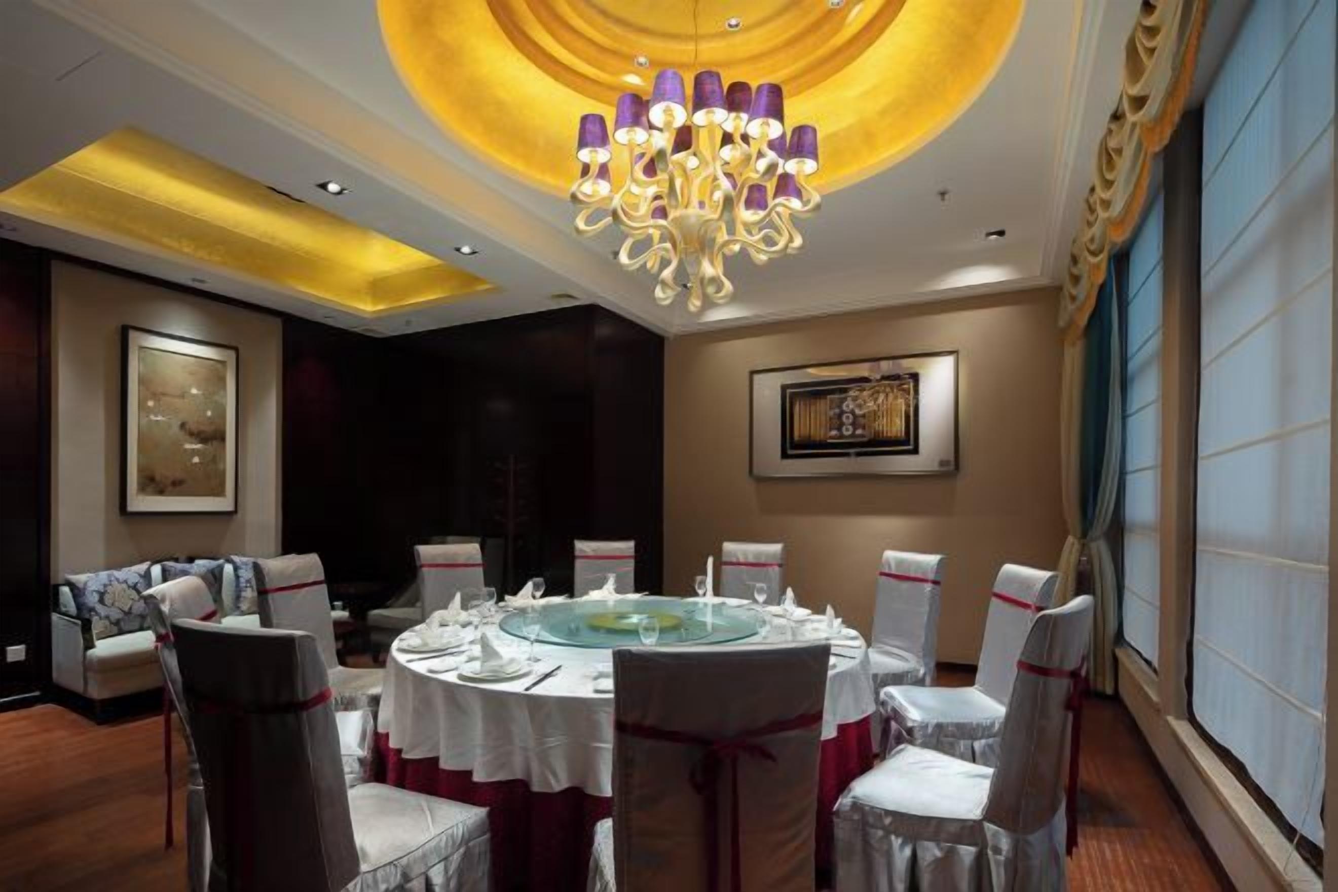 A dining room with a round table, chairs, and a chandelier.