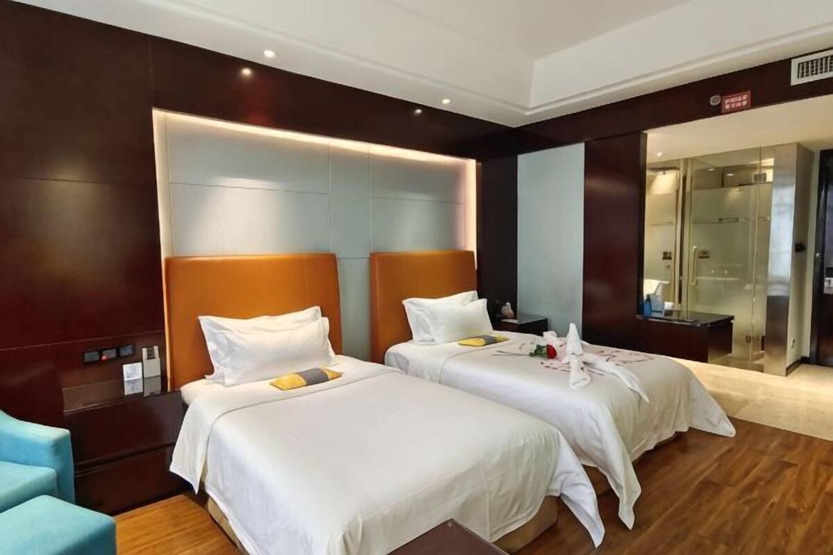 Ein Hotelzimmer mit zwei Betten, einer Duschkabine und einer Sitzecke.