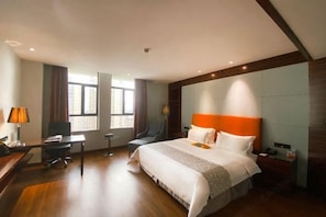 A hotel room with a large bed, a desk, a chair, and a window. - Silverhall Grand Hotel (Qichun)