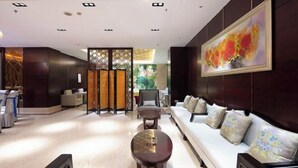 Un lobby moderno con un sofá, dos mesas redondas y un separador decorativo.
