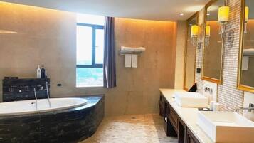 A modern bathroom with a large bathtub, two sinks, and a large mirror.