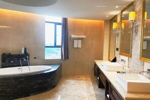 Un baño moderno con una bañera grande, dos lavamanos y un espejo amplio.