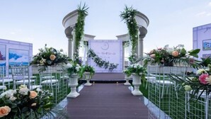 Un pasillo nupcial con sillas blancas y decoración floral.