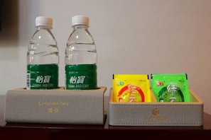 Two bottles of green beverage and two packets of snacks in a box labeled "Complimentary." - Silverhall Grand Hotel (Qichun)