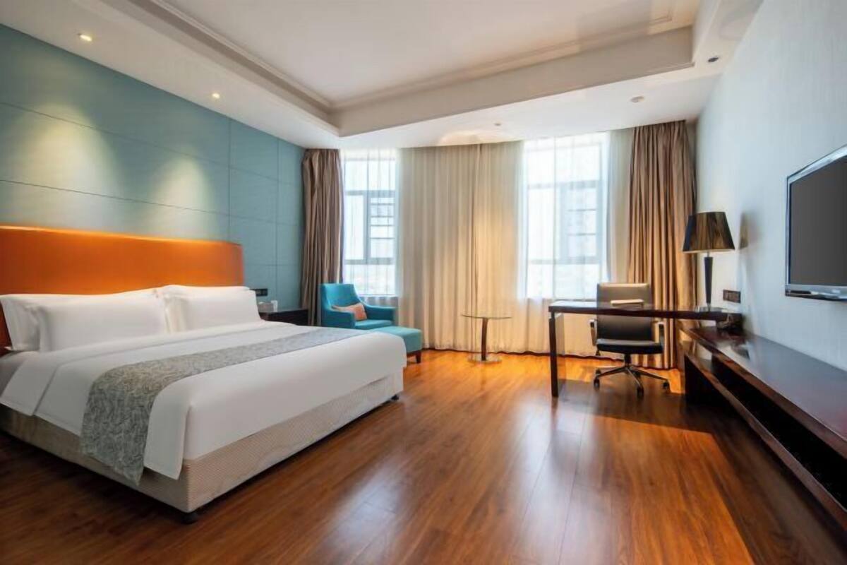 Ein Hotelzimmer mit einem großen Bett, einem Schreibtisch, einem Stuhl und einem Fernseher.