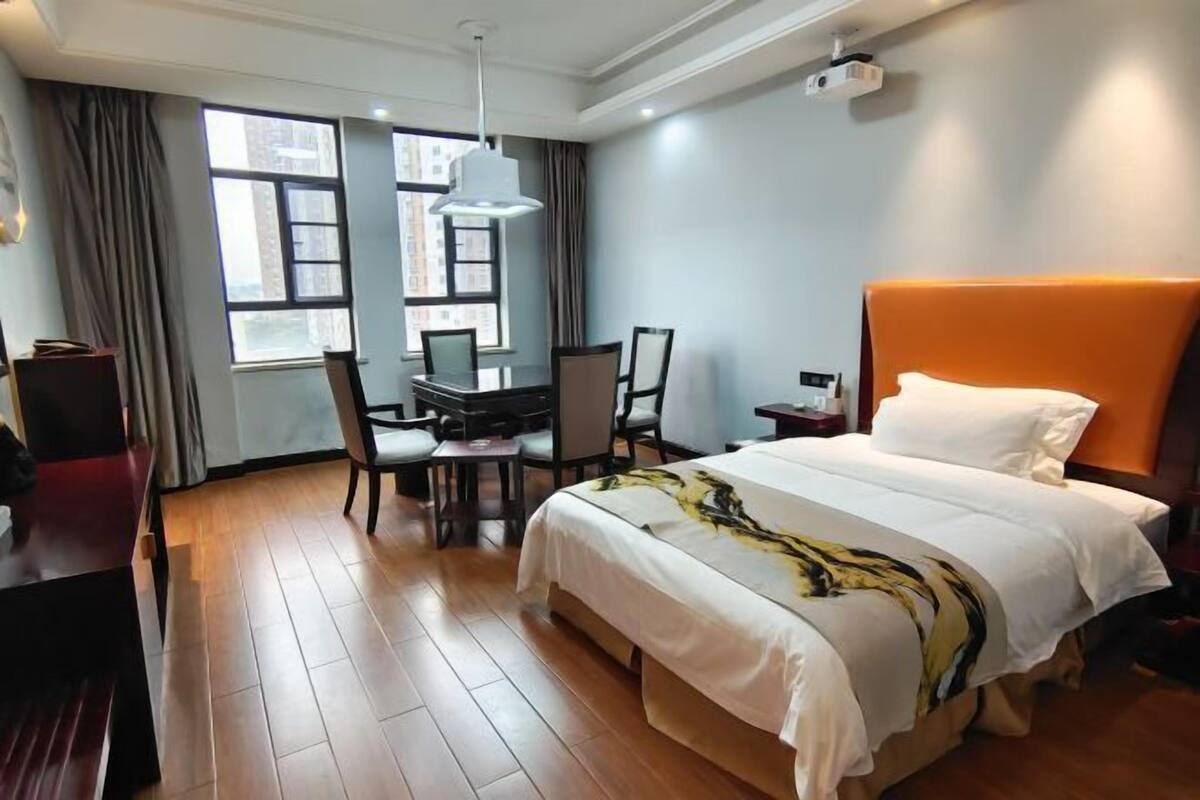 Ein Hotelzimmer mit Bett, Schreibtisch, Stühlen und Blick durch große Fenster.